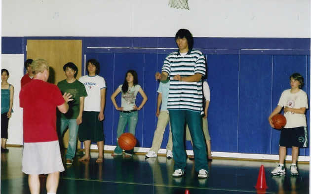 Portland Trailblazers Community Outreach Youth Basketball Director Jerry Moss, back to camera, demonstrates a drill with Seung-jin Ha's help.